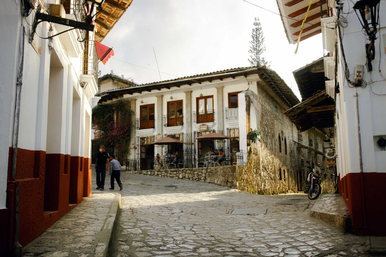 Sunlit cobblestone street in Cuetzalan with traditional architecture and locals walking.