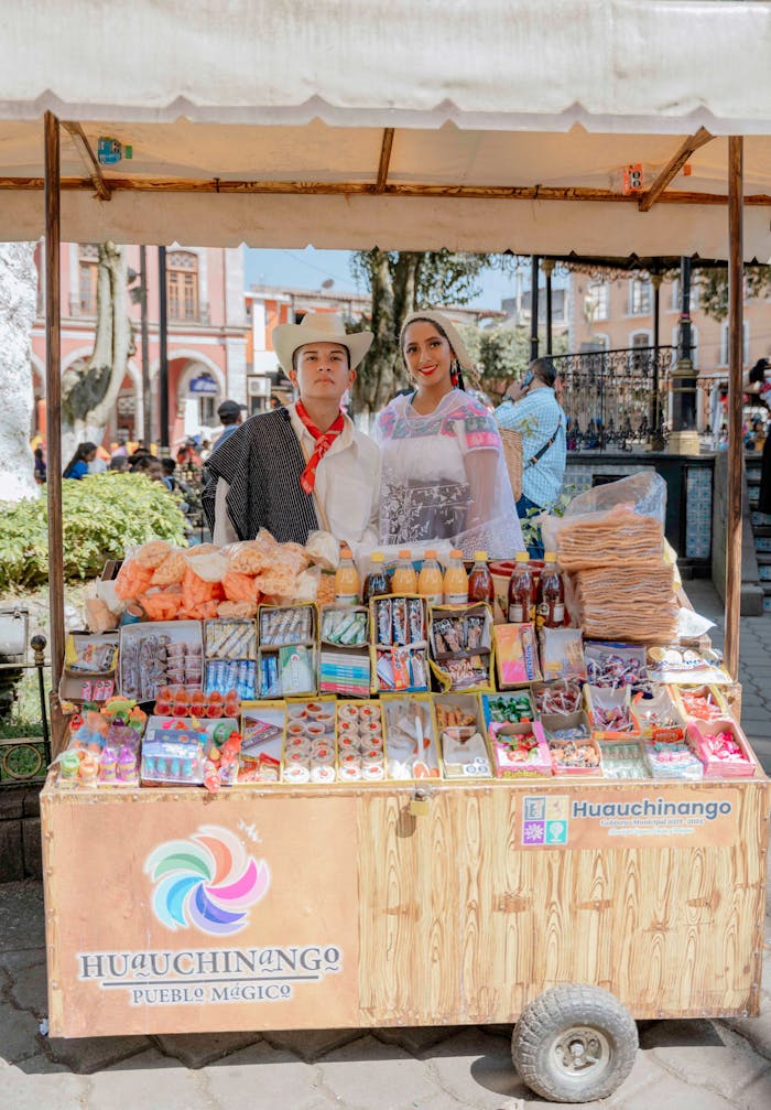 Traditional candy stall with vendors in Huauchinango, Mexico, showcasing local sweets and culture.